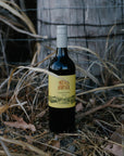 Blind Corner Organic and Biodynamic Margaret River Sangiovese bottle in front of a fence post and tall grass.