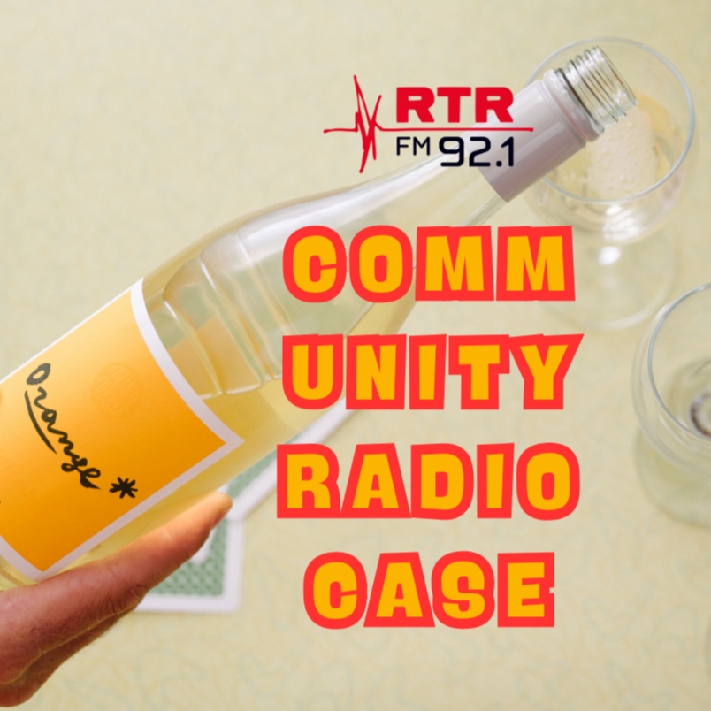 Bottle of Orange* in Colour wine with a glass, held by a hand, on a beige surface with 'RTR FM 92.1' logo and text overlay.