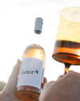 Person holding a bottle of Blind Corner Organic Biodynamic Pinot Grigio wine with a glass being filled.