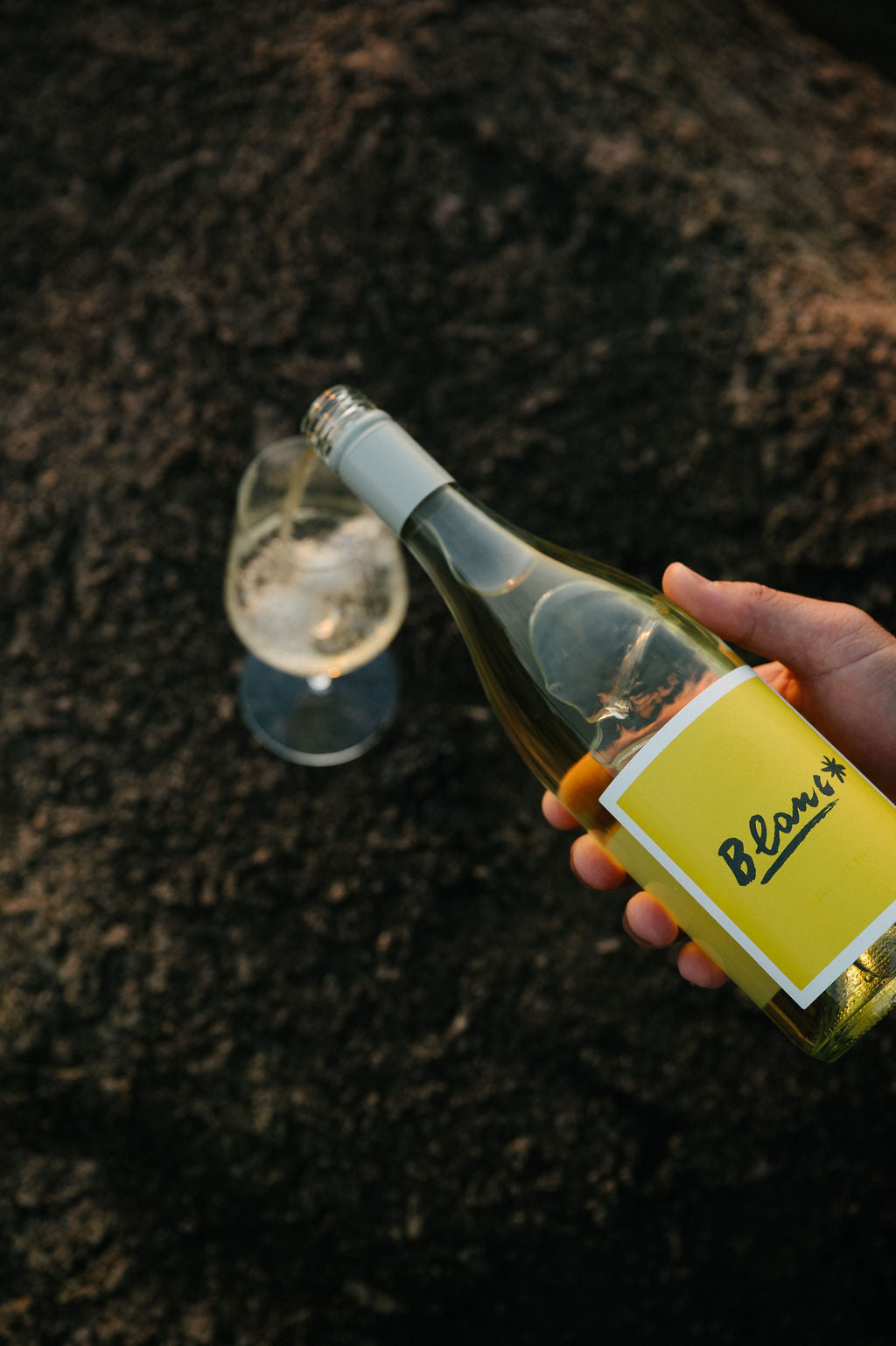 Person pours a glass of Blind Corner Organic Margaret River Blanc - a Sauvignon Blanc and Semillon blend - on a natural stone background