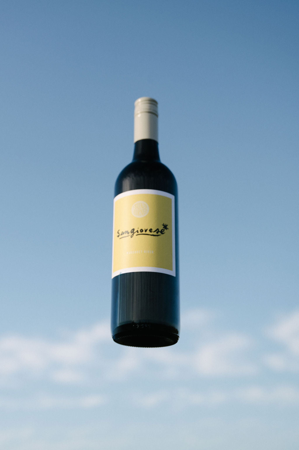 Blind Corner Organic Sangiovese wine bottle against a bright blue sky