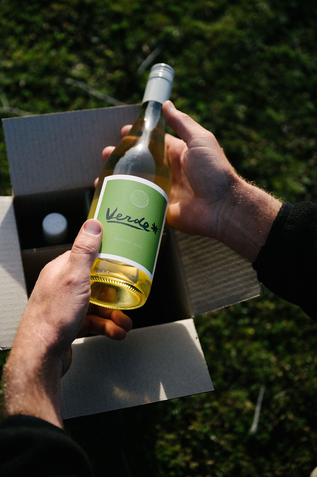 Person holds a bottle of Blind Corner Organic Verde wine selected from the Wine Club 4-pack box.