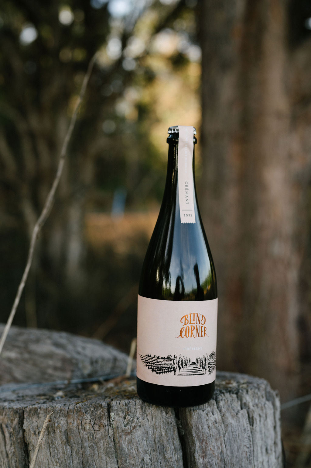 Blind Corner Organic and Biodynamic Margaret River Cremant bottle sitting on a fence post in the bush