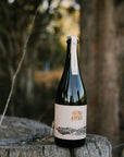 Blind Corner Organic and Biodynamic Margaret River Cremant bottle sitting on a fence post in the bush