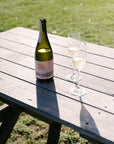 Bottle of Blind Corner Organic and Biodynamic Margaret River Cremant and two freshly poured glasses on a wooden table outdoors