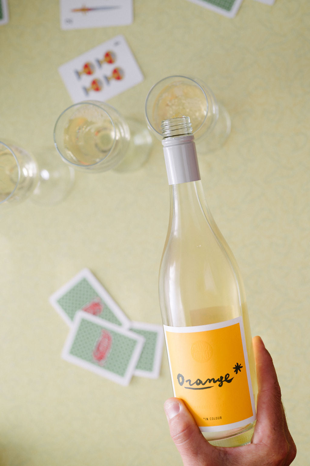 Live the Orange* in Colour life. Blind Corner Organic and Biodynamic Margaret River Orange* in Colour Skin Contact Blend being poured into glasses, playing cards scattered around it