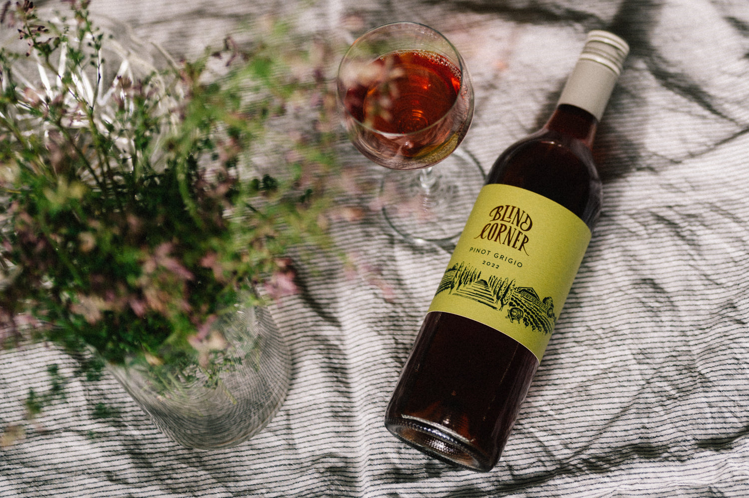Blind Corner Organic and Biodynamic Margaret River Pinot Grigio on a picnic blanket with a freshly poured glass and bunch of flowers