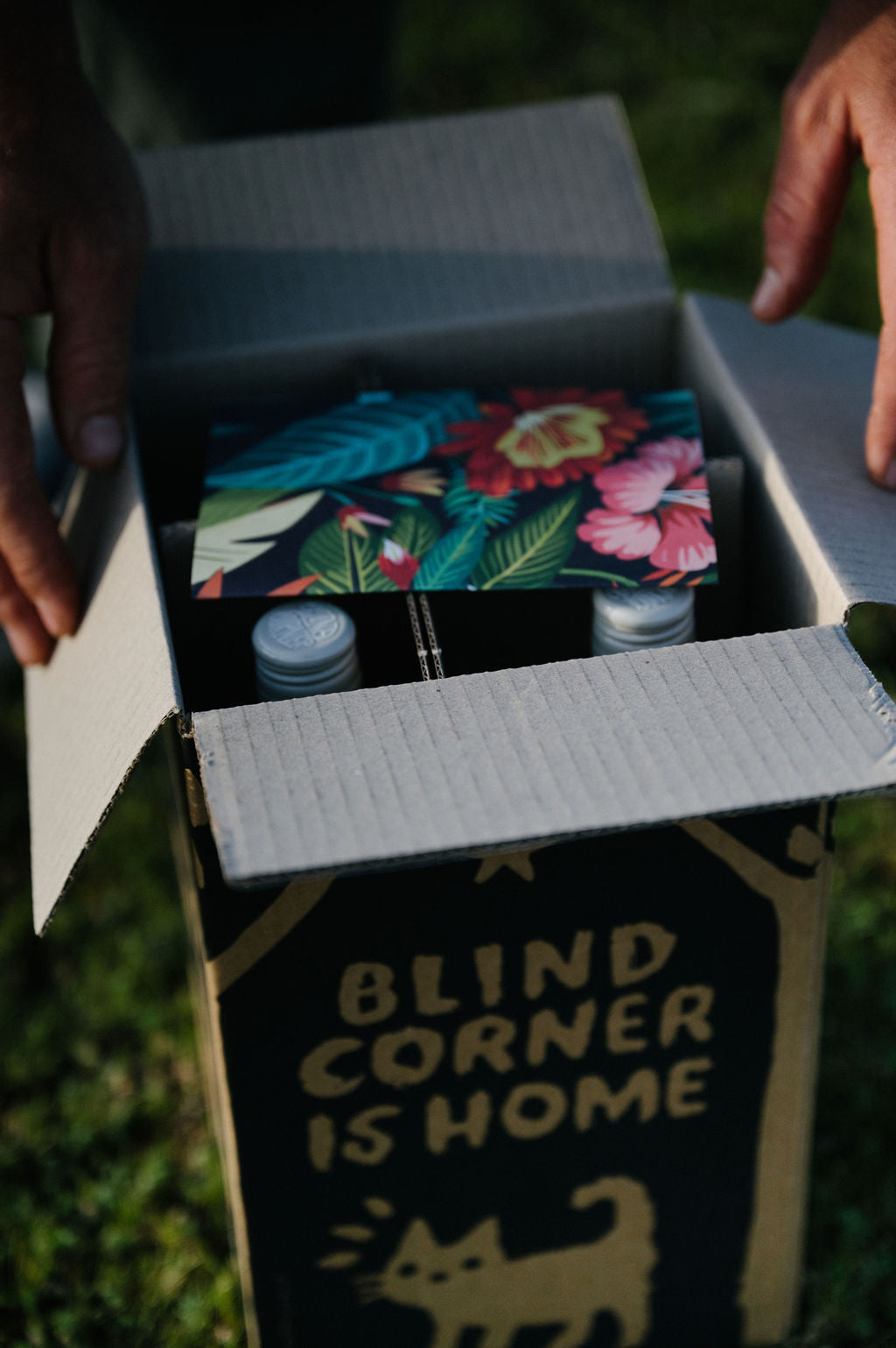 Open wine club box containing colourful cards and bottles of organic wine with 'Blind Corner is Home' text on the side.