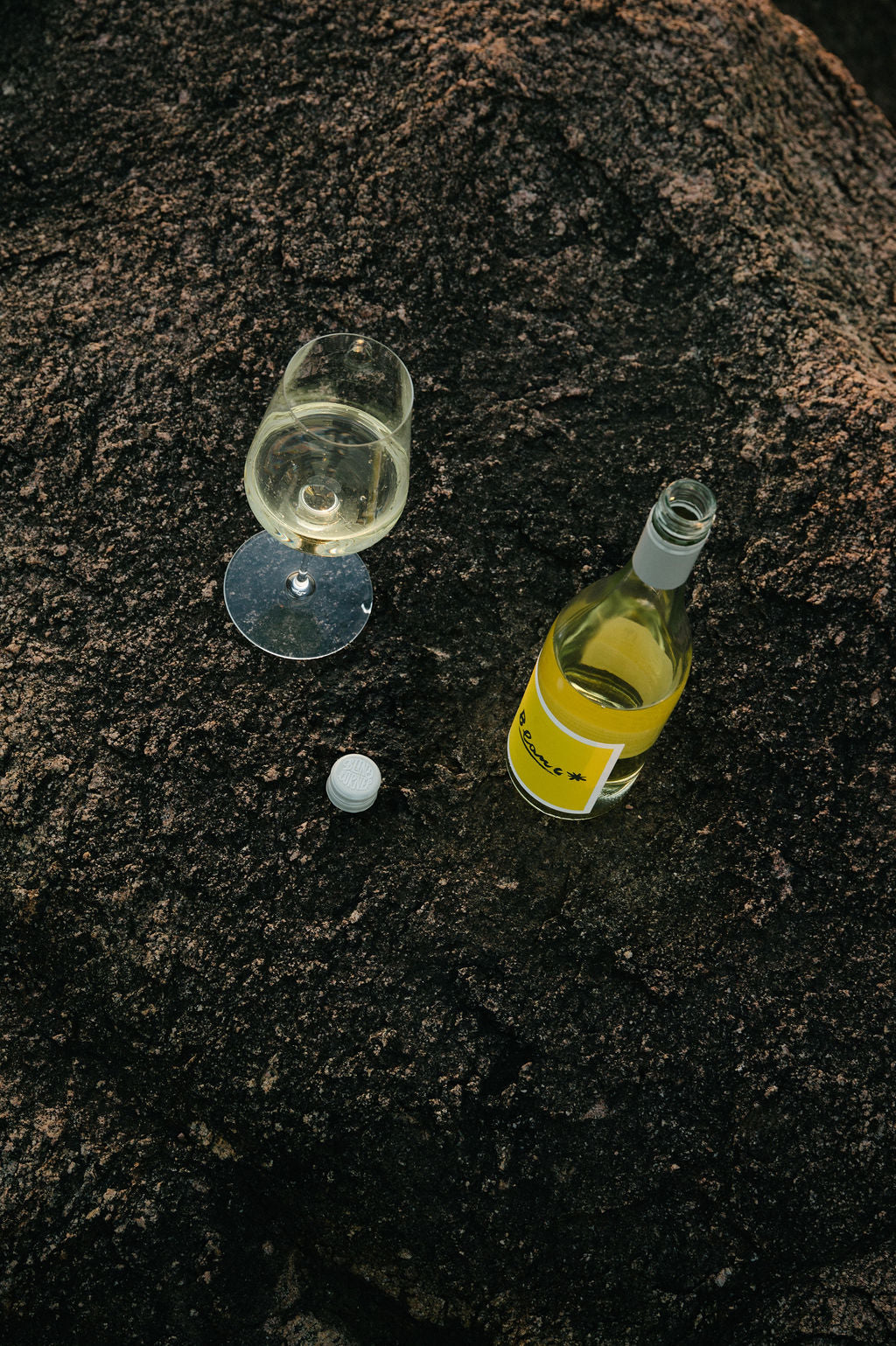 Bottle of Blind Corner Organic Blanc and a poured glass sitting on a textured stone background